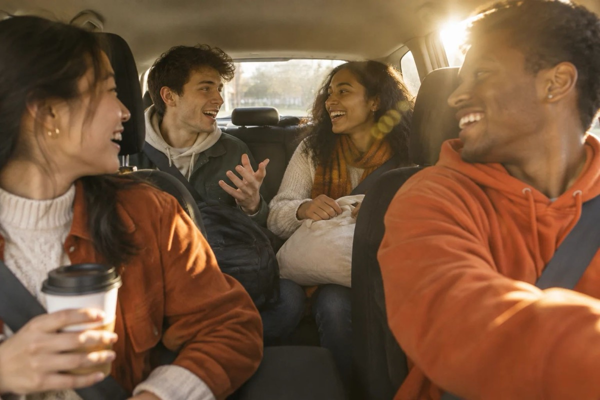Four friends laughing and talking together in a car in warm afternoon light